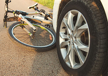 A bicycle trapped under the front bumper of a car after a crash.