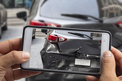 Car accident victim taking a picture of their damaged vehicle as evidence for a personal injury lawsuit