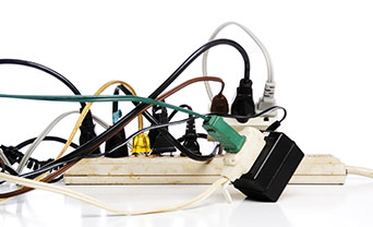 A dangerously overloaded power strip with many plugs creating an electrocution risk.