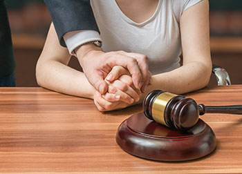 A supportive wrongful death attorney shows compassion for his client by holding her hand.